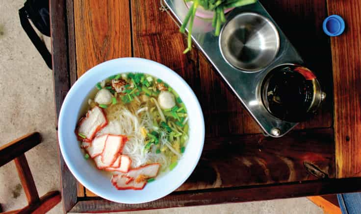 Instagram feed from one page website template, showing white dish of Laotian food on a vintage wooden table with condiments.