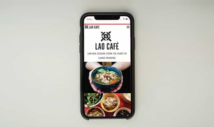 Lao café website on mobile phone on pale green background.