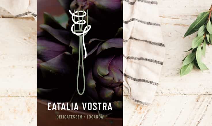 Restaurant logo for Eatalia Vostra (a fork with a 'V' in it and spaghetti style graphic wrapping round forming the 'E') on an deep purple artichoke background, with a further background of cream linen and plaster.