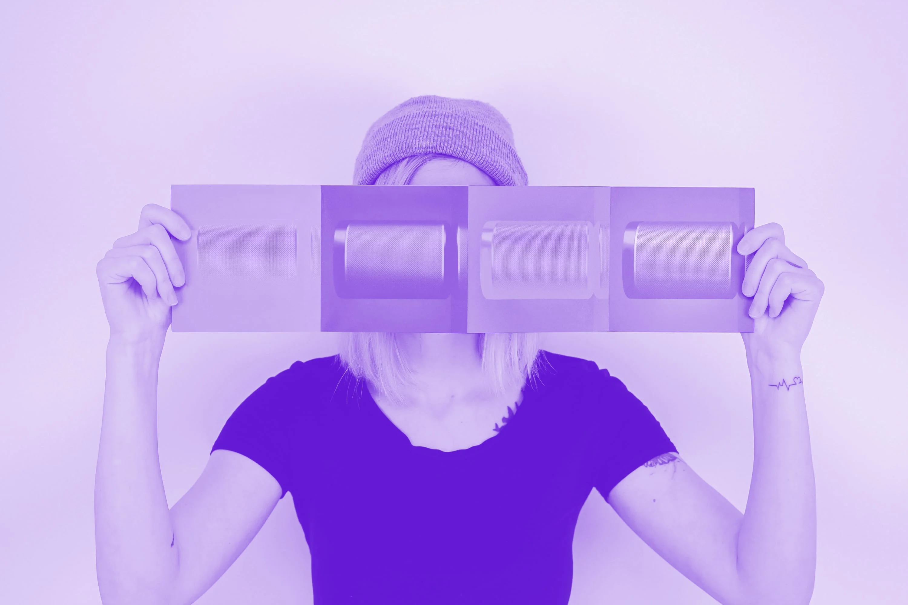 woman in beanie hat holding printed brochure panel purple toned