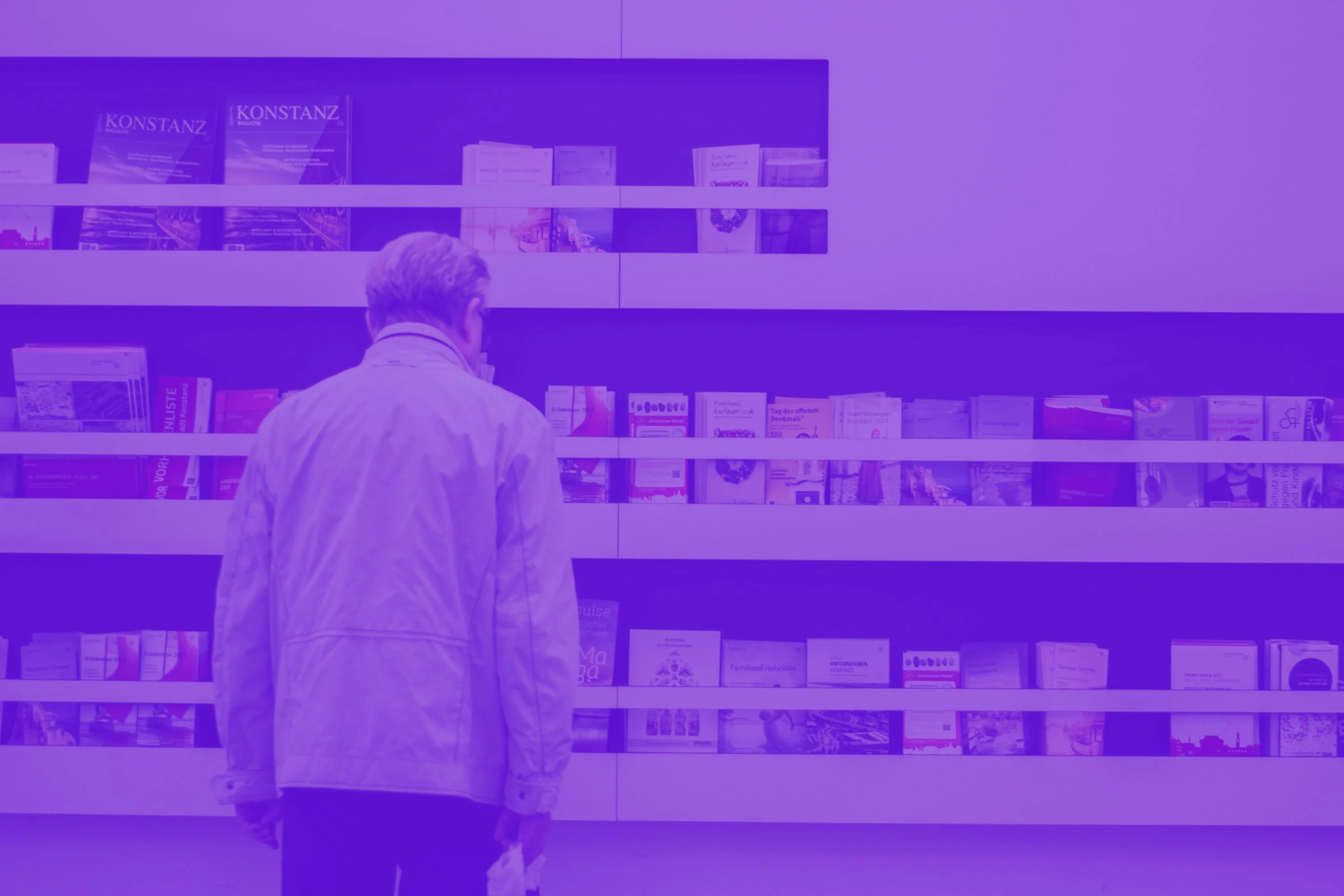 man browsing brochures on display shelves exhibition purple toned