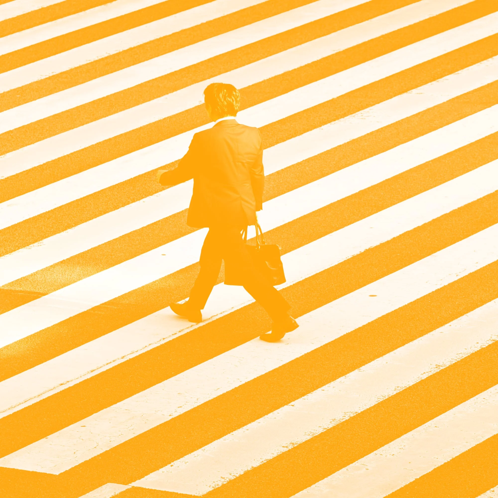businessman silhouette walking across zebra crossing amber toned