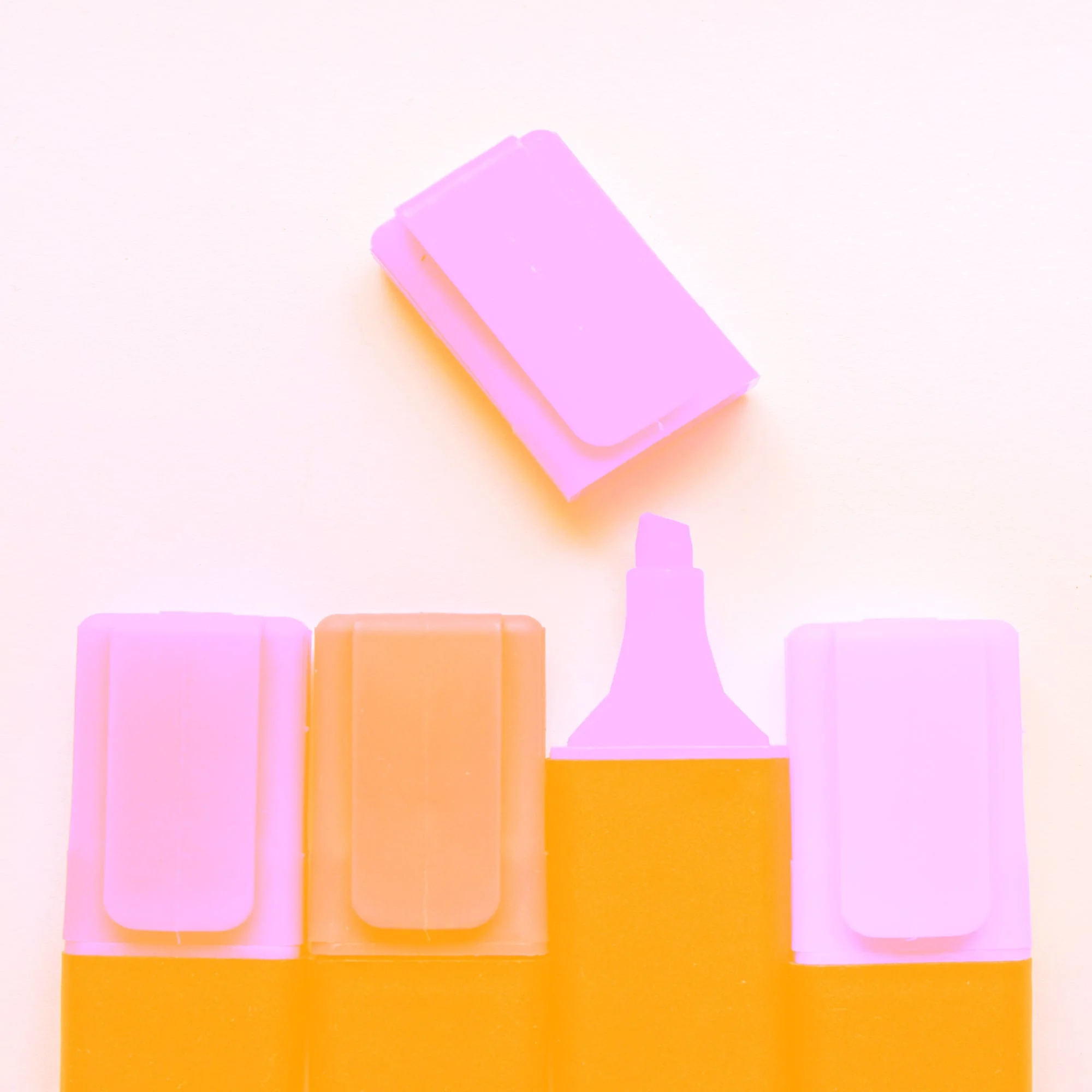pink highlighter markers and caps arranged on white background