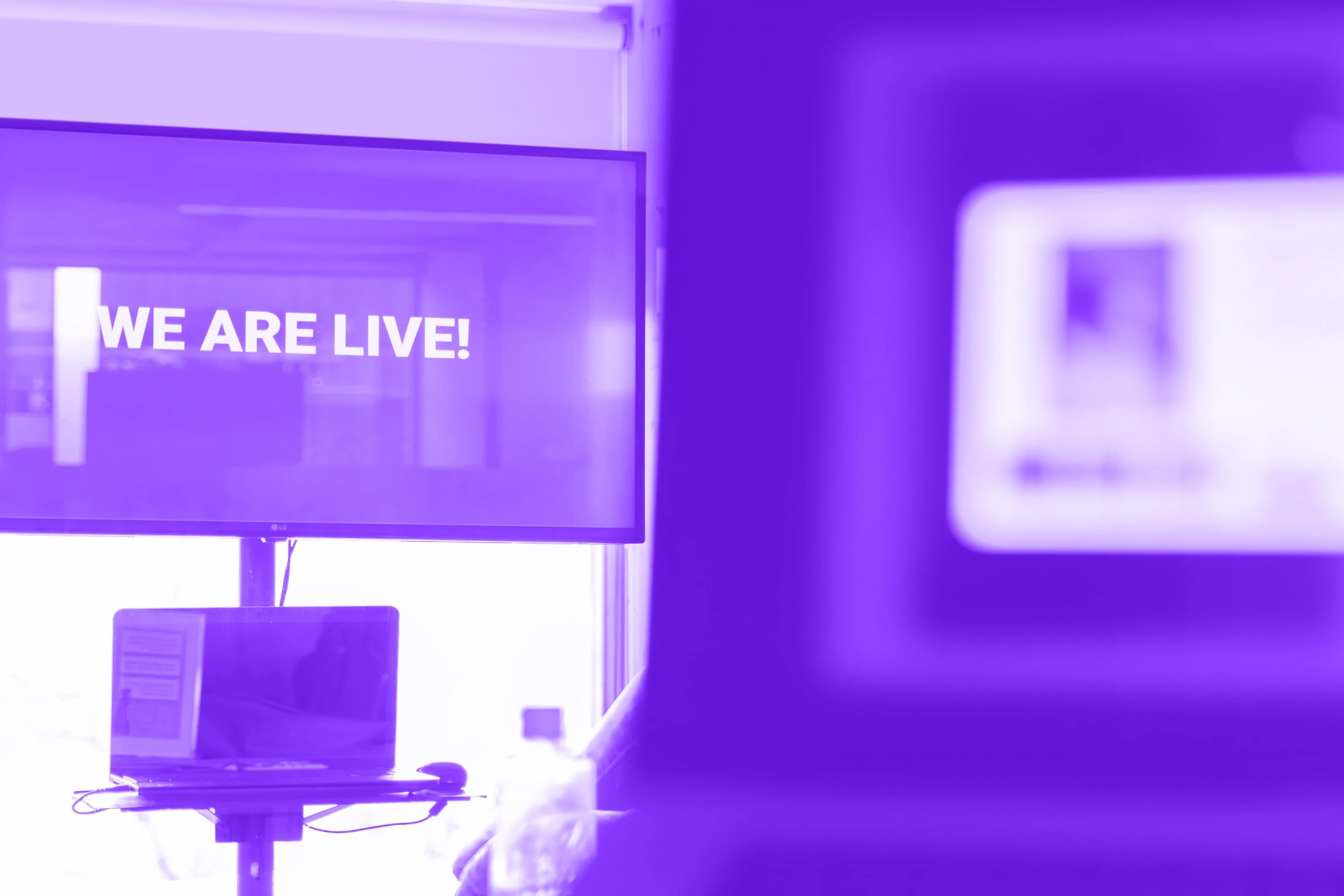 lg monitor displaying we are live text presentation purple toned
