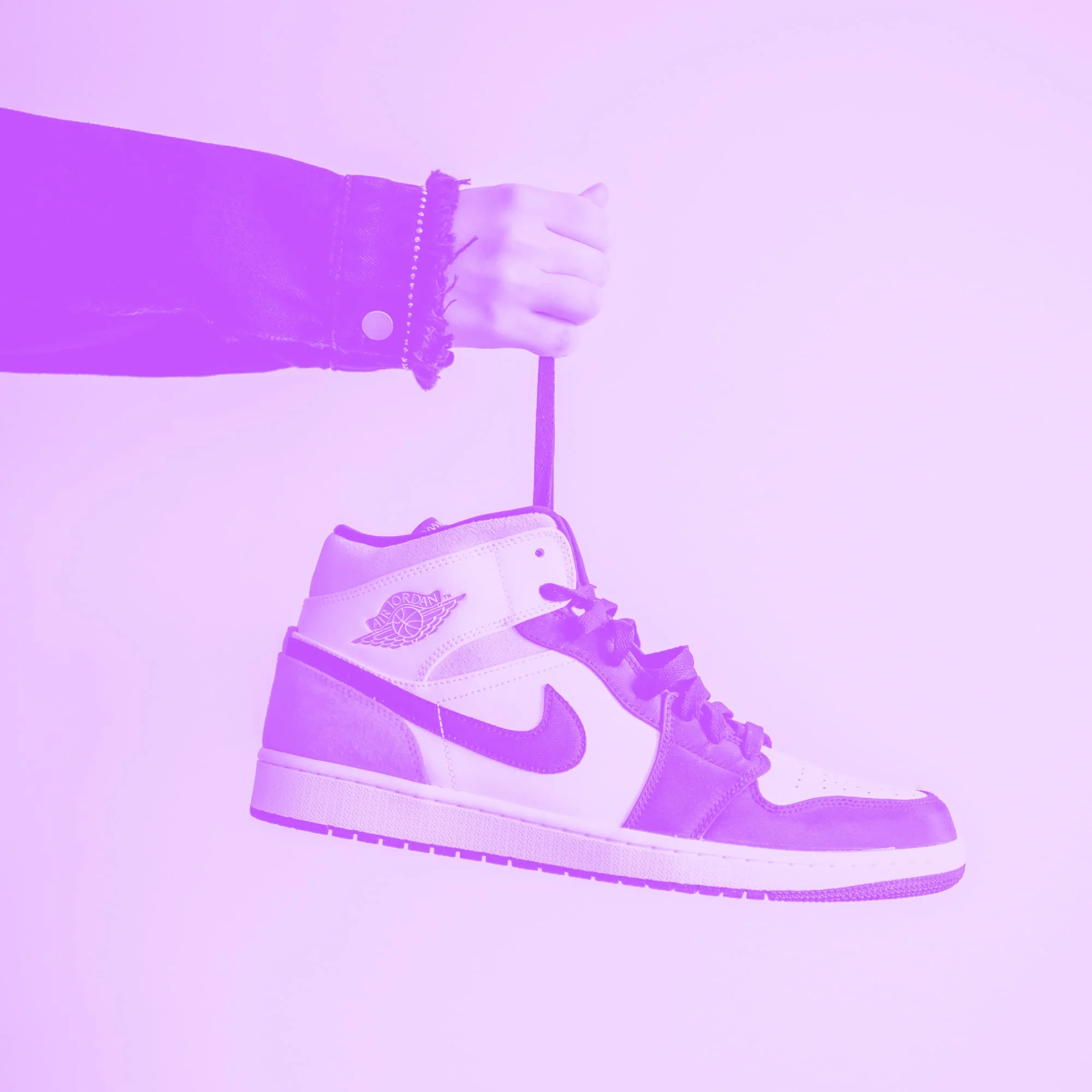 hand holding air jordan 1 sneaker by lace dangling purple toned