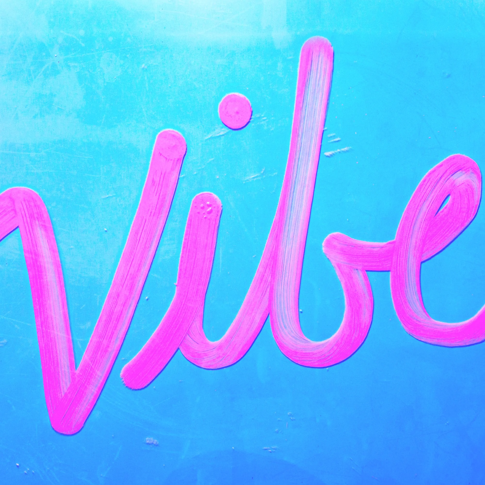 close up of vibe text painted in hot pink script on teal painted wall