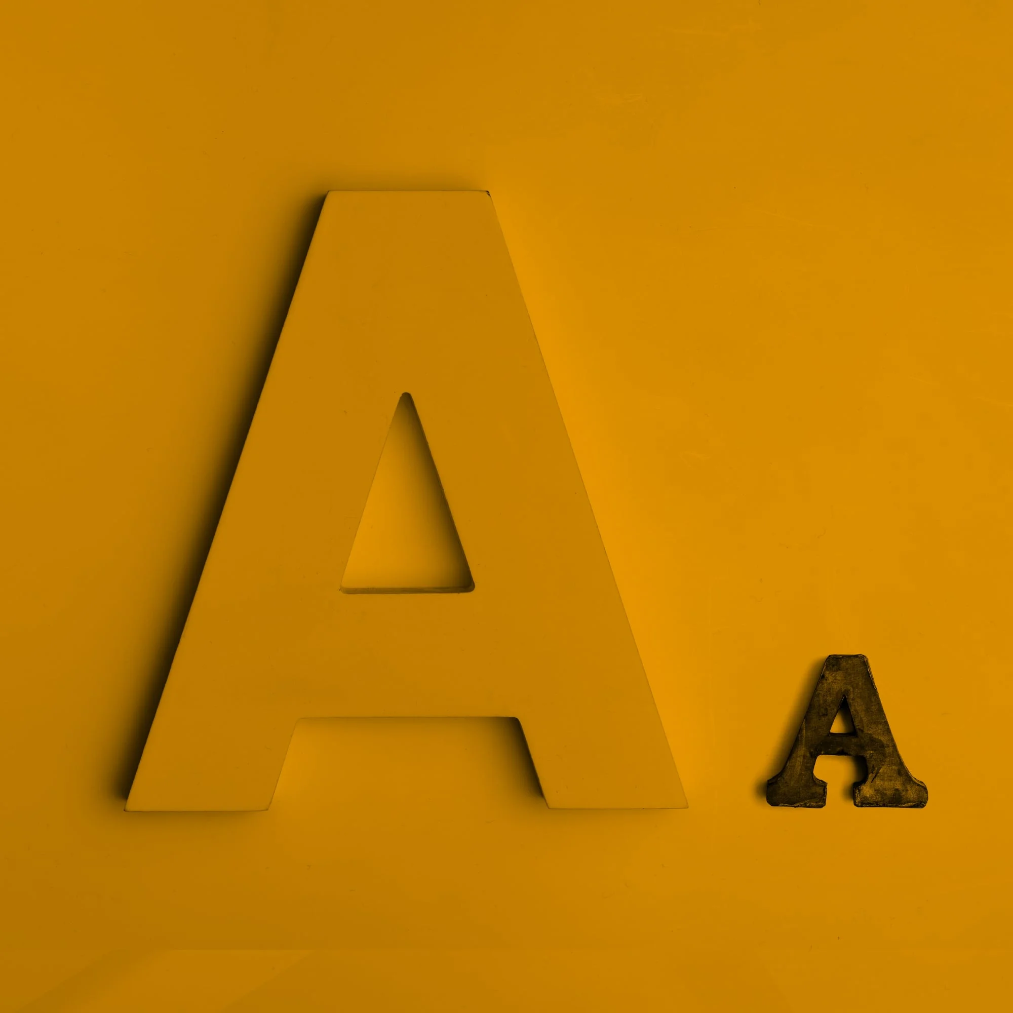 large letter a font comparison two sizes golden amber background typography