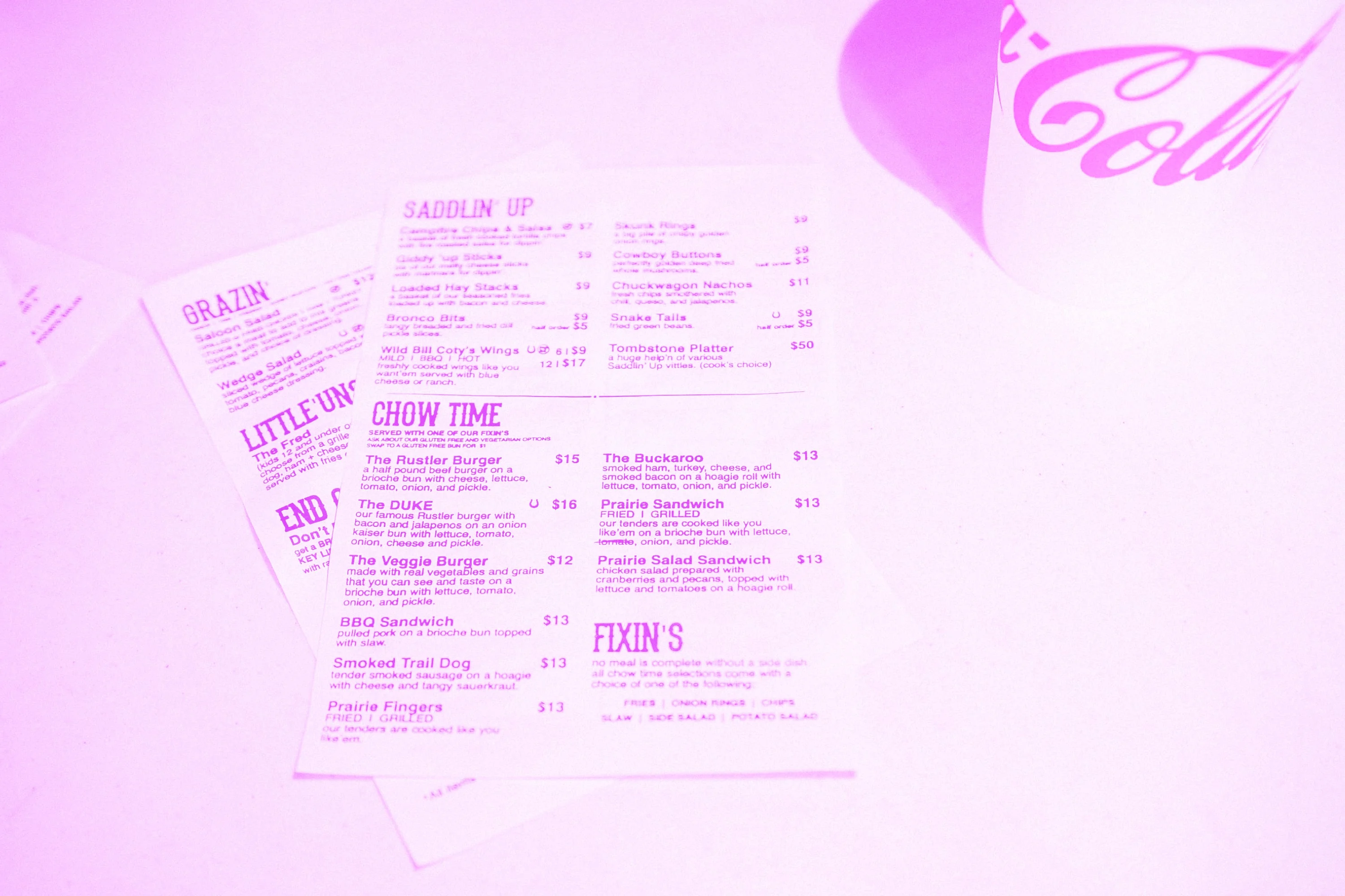 american diner paper menus spread out on table with coca cola cup pink purple