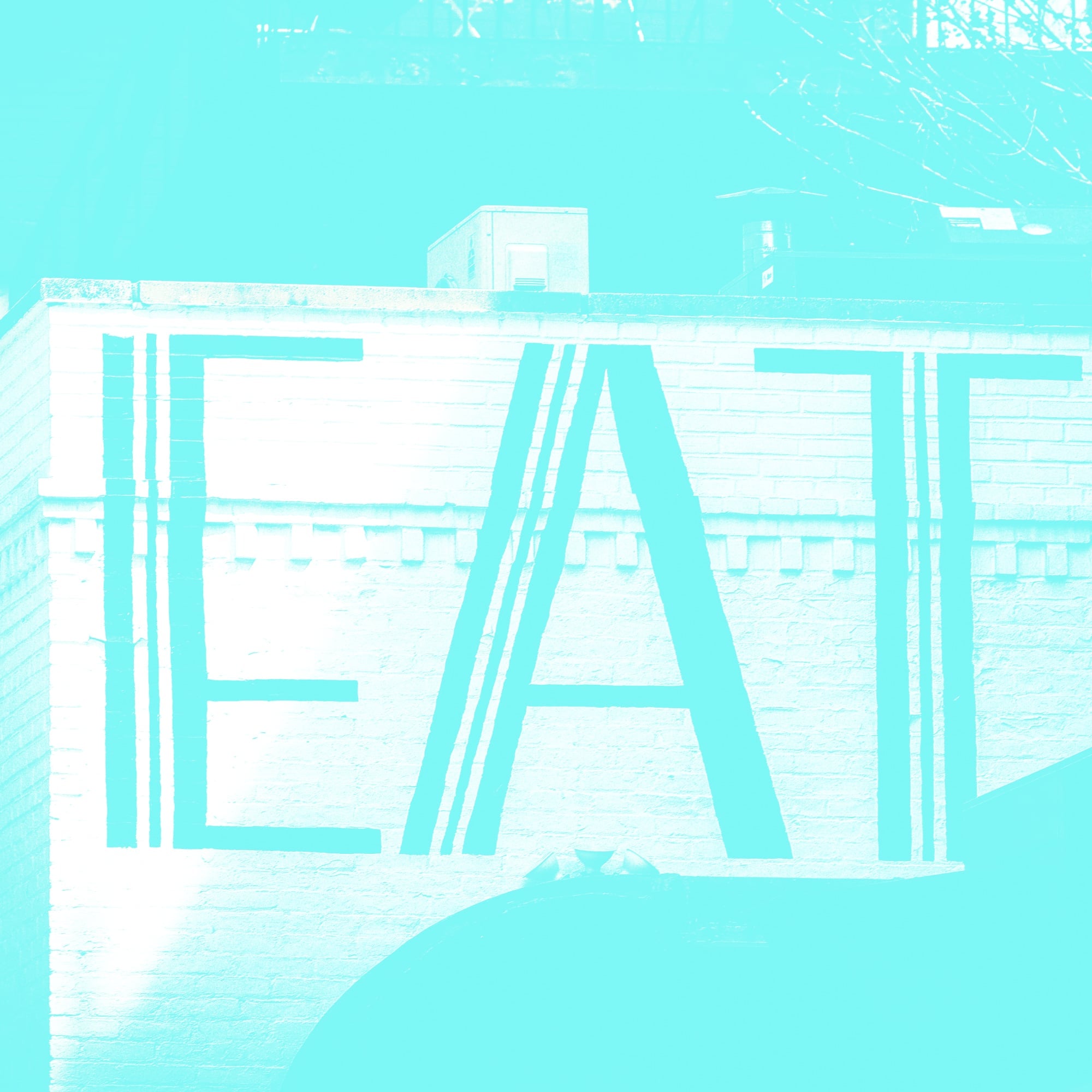 large eat bold typography letters on brick wall exterior teal toned