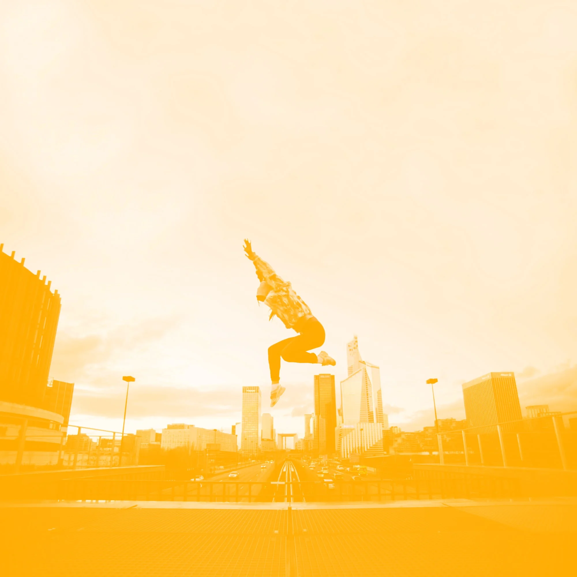 woman jumping high above city skyline with arms raised golden amber toned