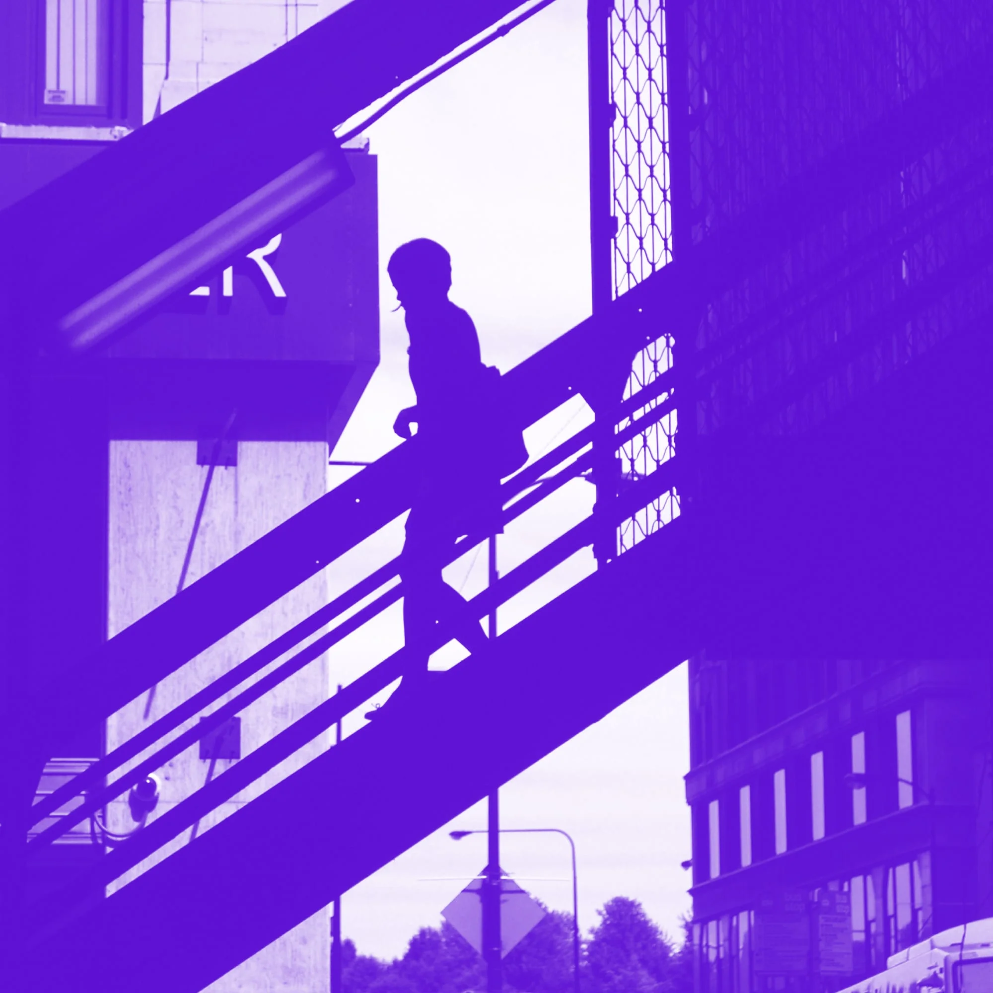 silhouette of person walking up fire escape stairs building exterior purple toned