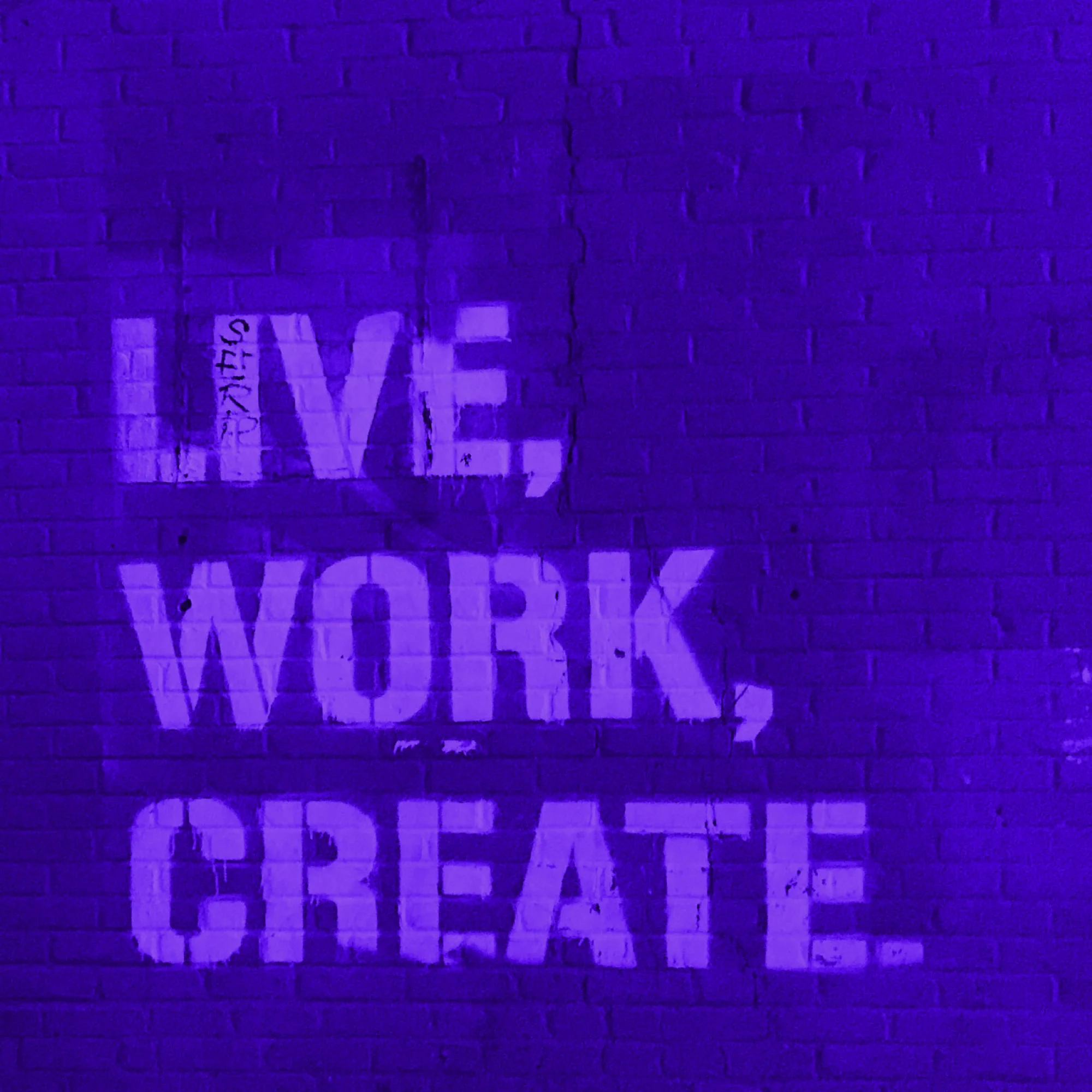 live work create stencil graffiti text on brick wall purple toned
