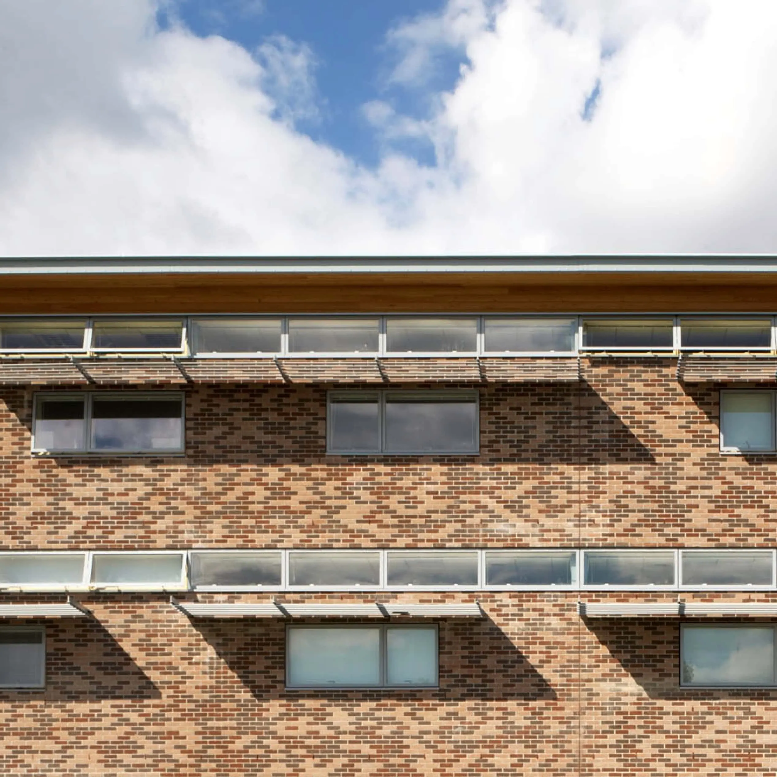 Brick building facade with horizontal strip windows beneath blue sky