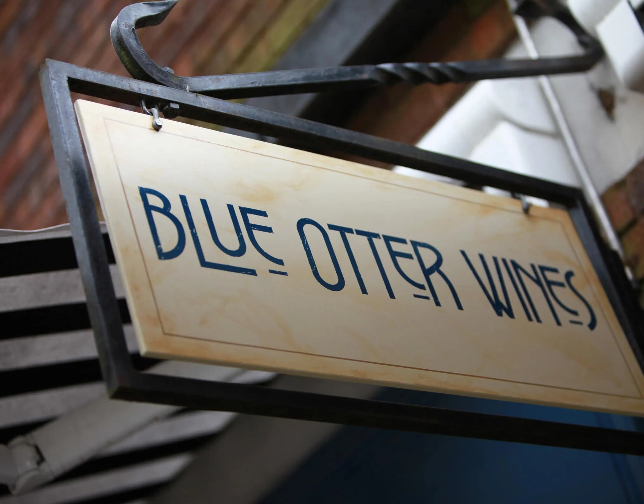 Hanging exterior sign for Blue Otter Wines on a metal bracket