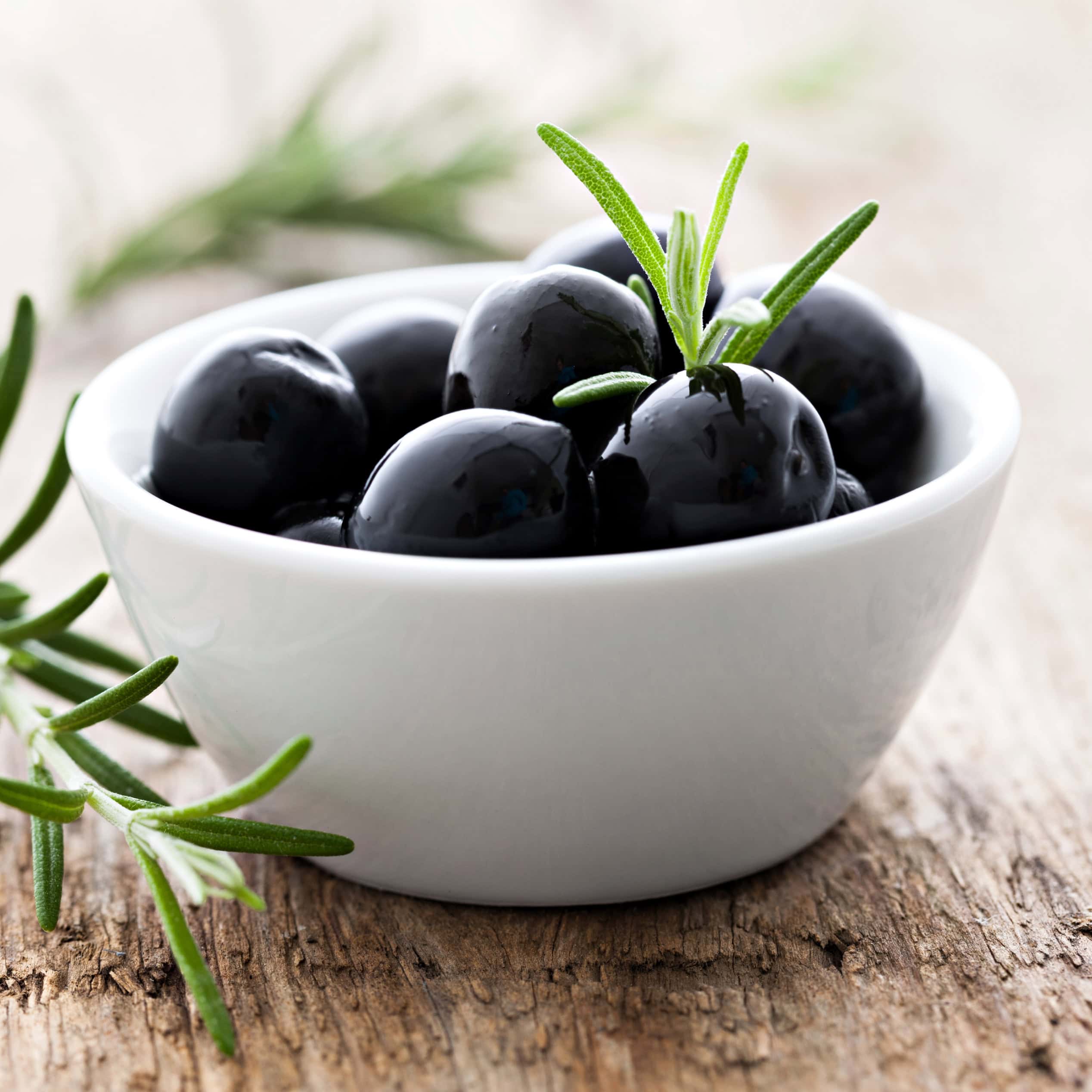 Bowl of glossy black olives garnished with rosemary