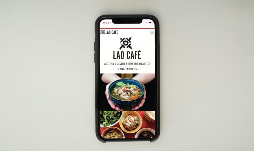 Lao café website on mobile phone on pale green background.
