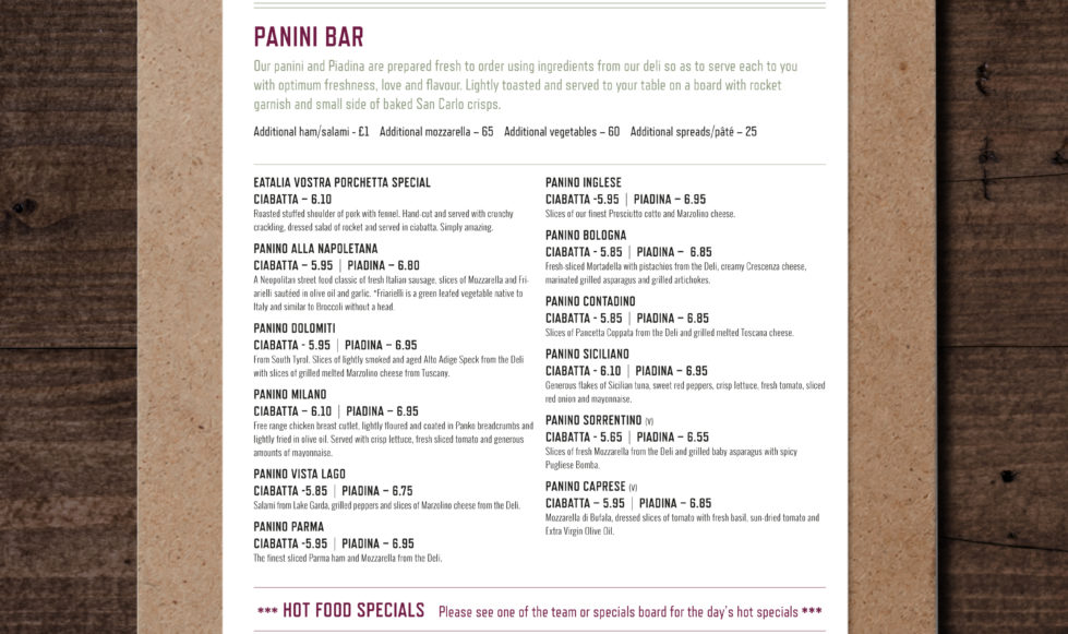 Dark wood background with a front view of a clip board holding a white sheet of paper with the menu for Eatalia Vostra.
