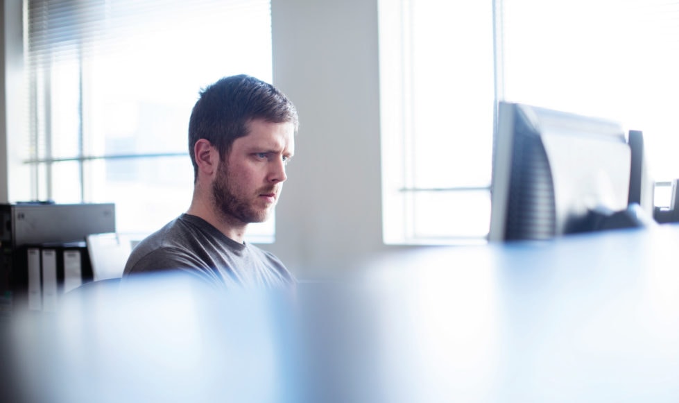 Tech website developer Bright image of a person working at a desktop computer.