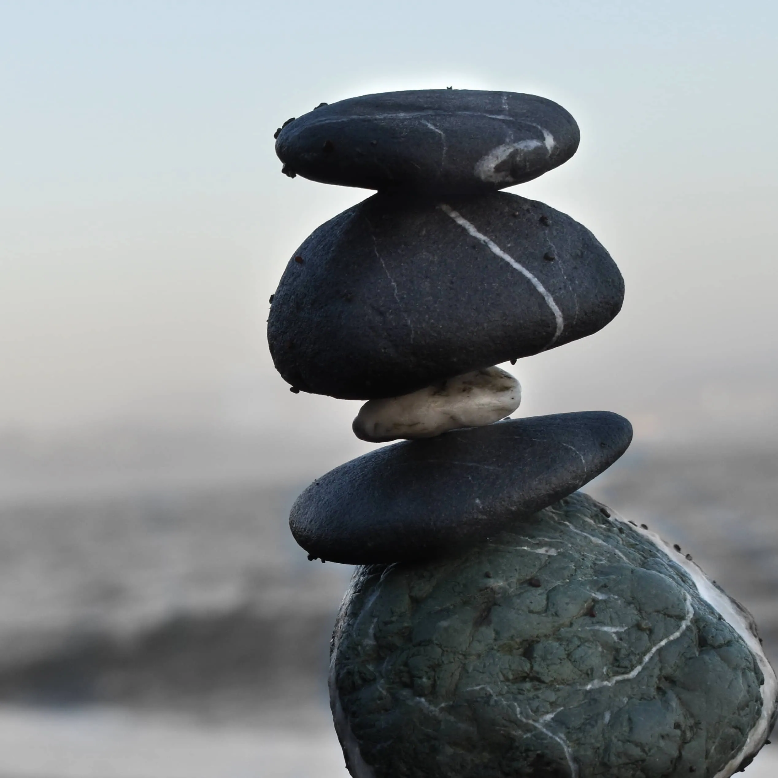 Stacked smooth beach stones balanced against a blurred sea backdrop