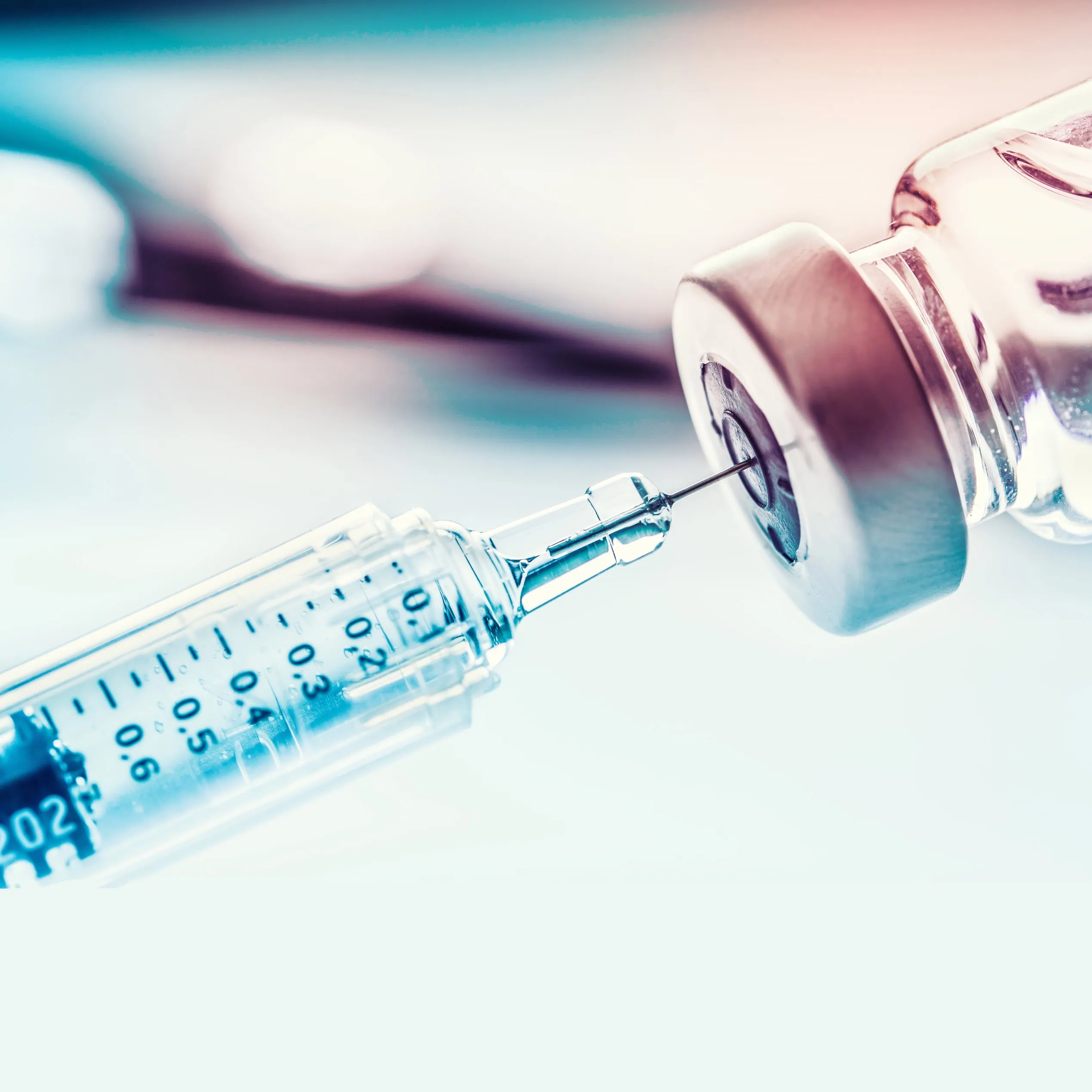 Close-up of a syringe drawing liquid from a medical vial