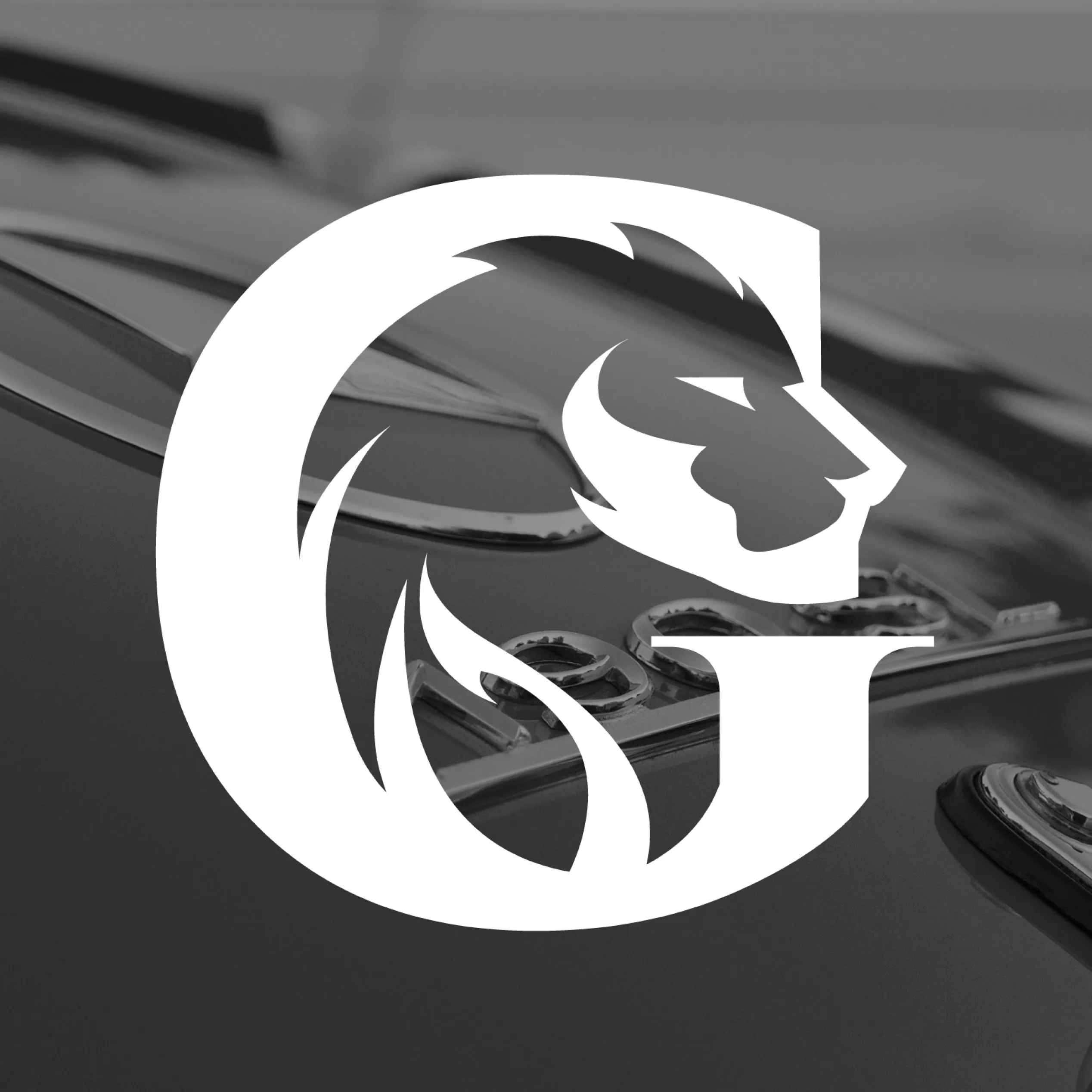 White lion-in-“G” emblem over a black-and-white close-up of a classic car detail