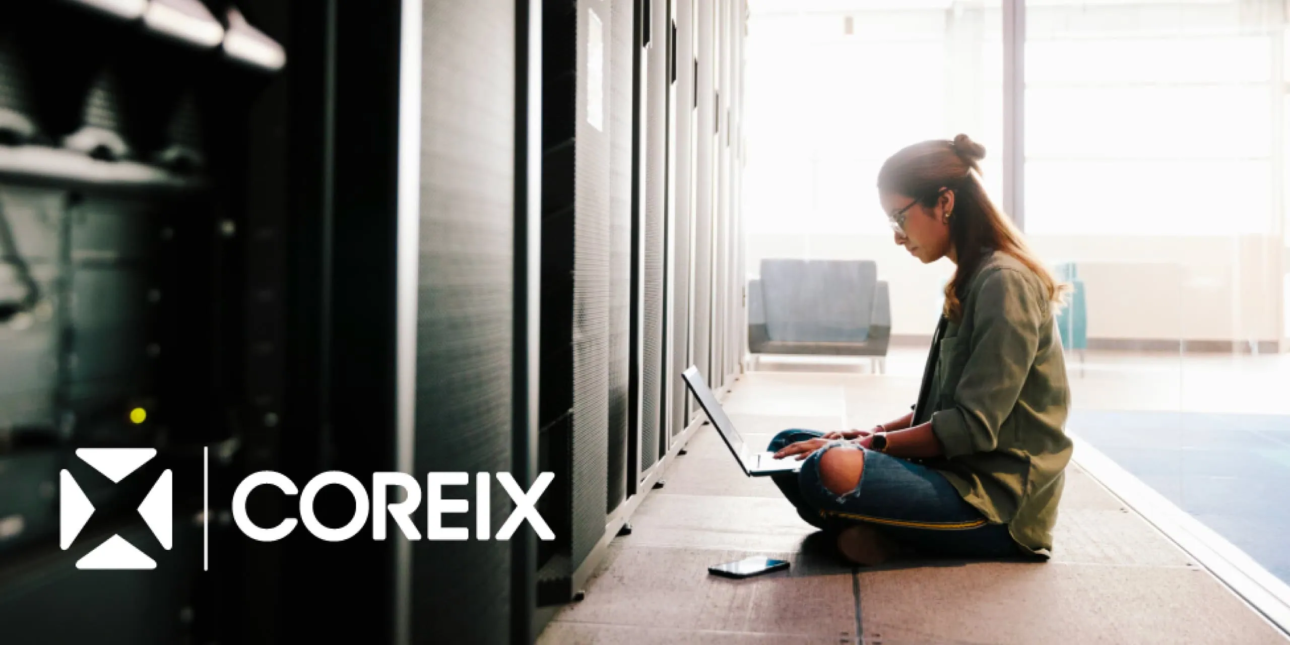Person working on a laptop beside server racks in a data centre.