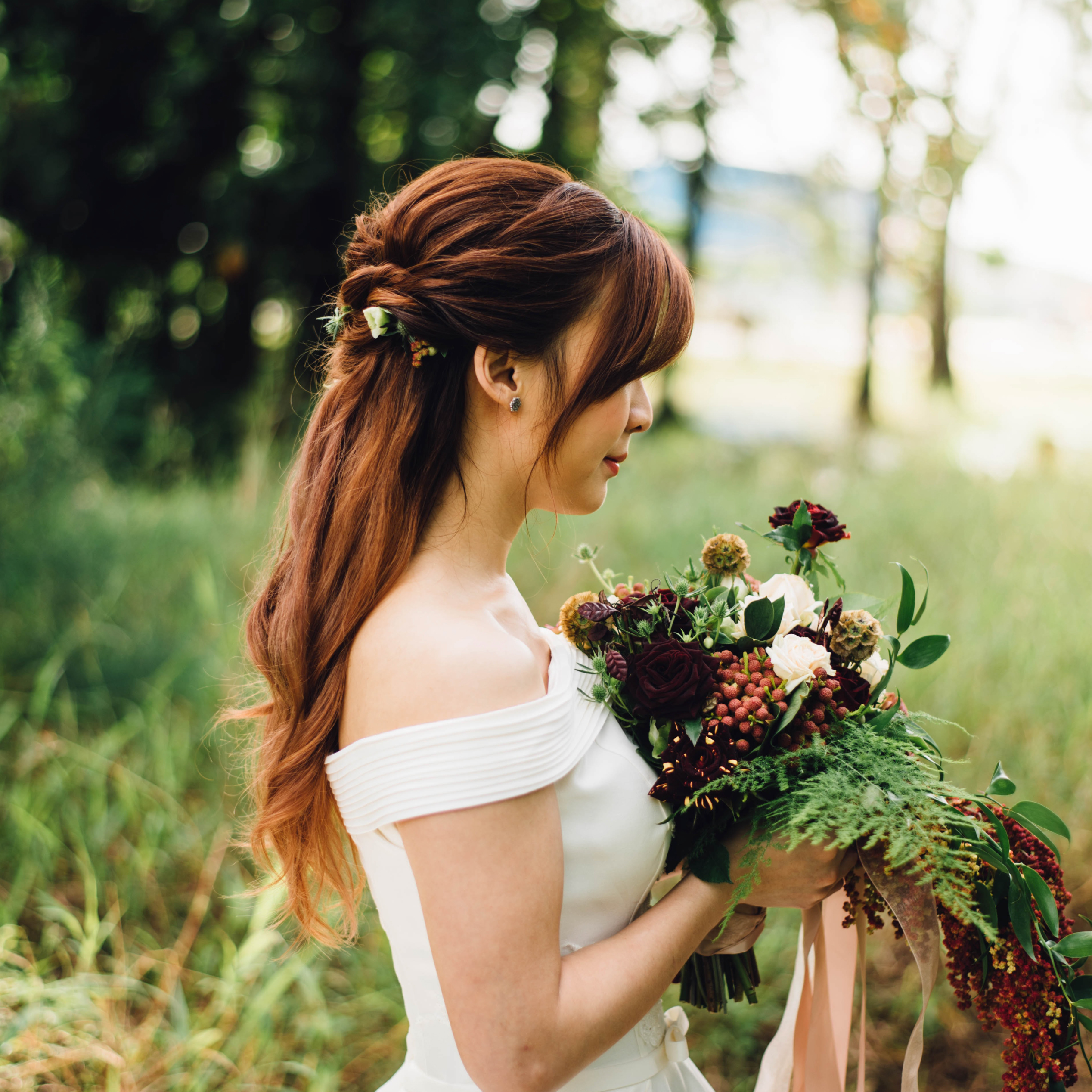 Bride in profile holding a bouquet outdoors