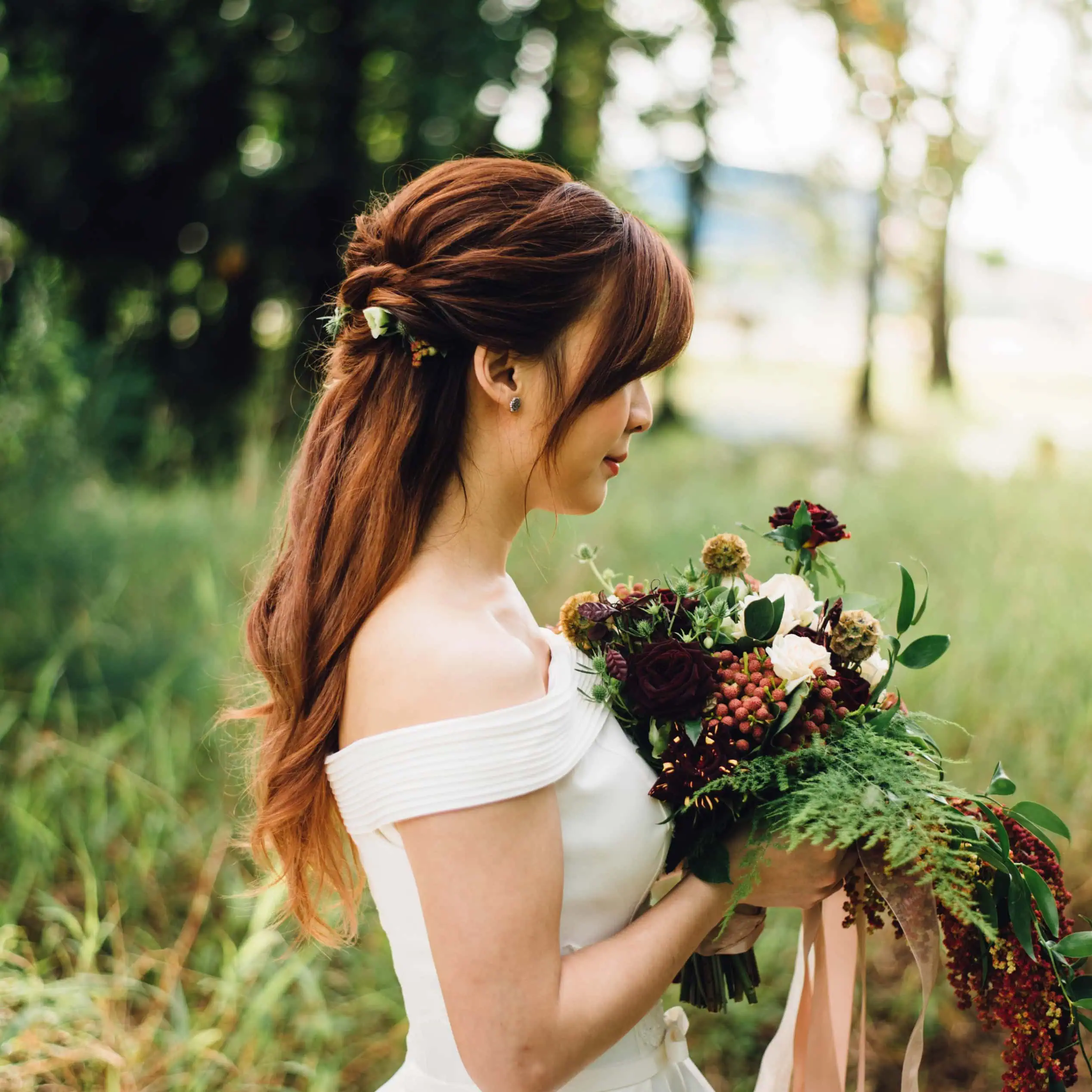 Bride in profile holding a bouquet outdoors