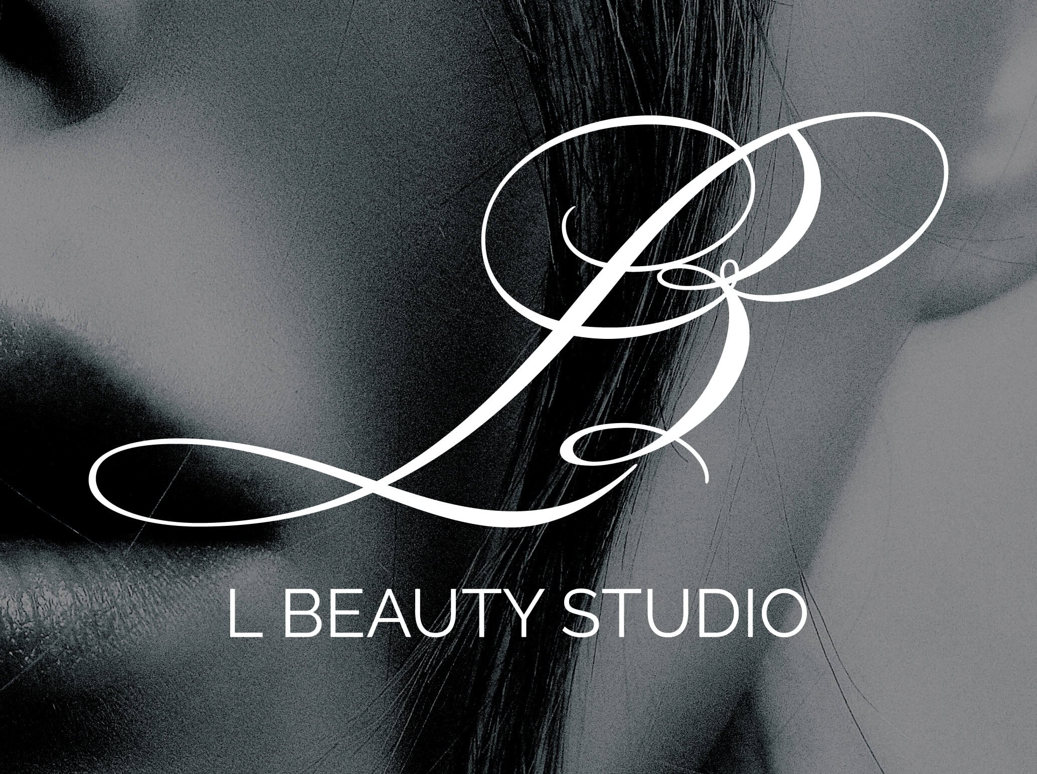 L Beauty Studio logo white out of a black and white close-up image of a beautiful face.