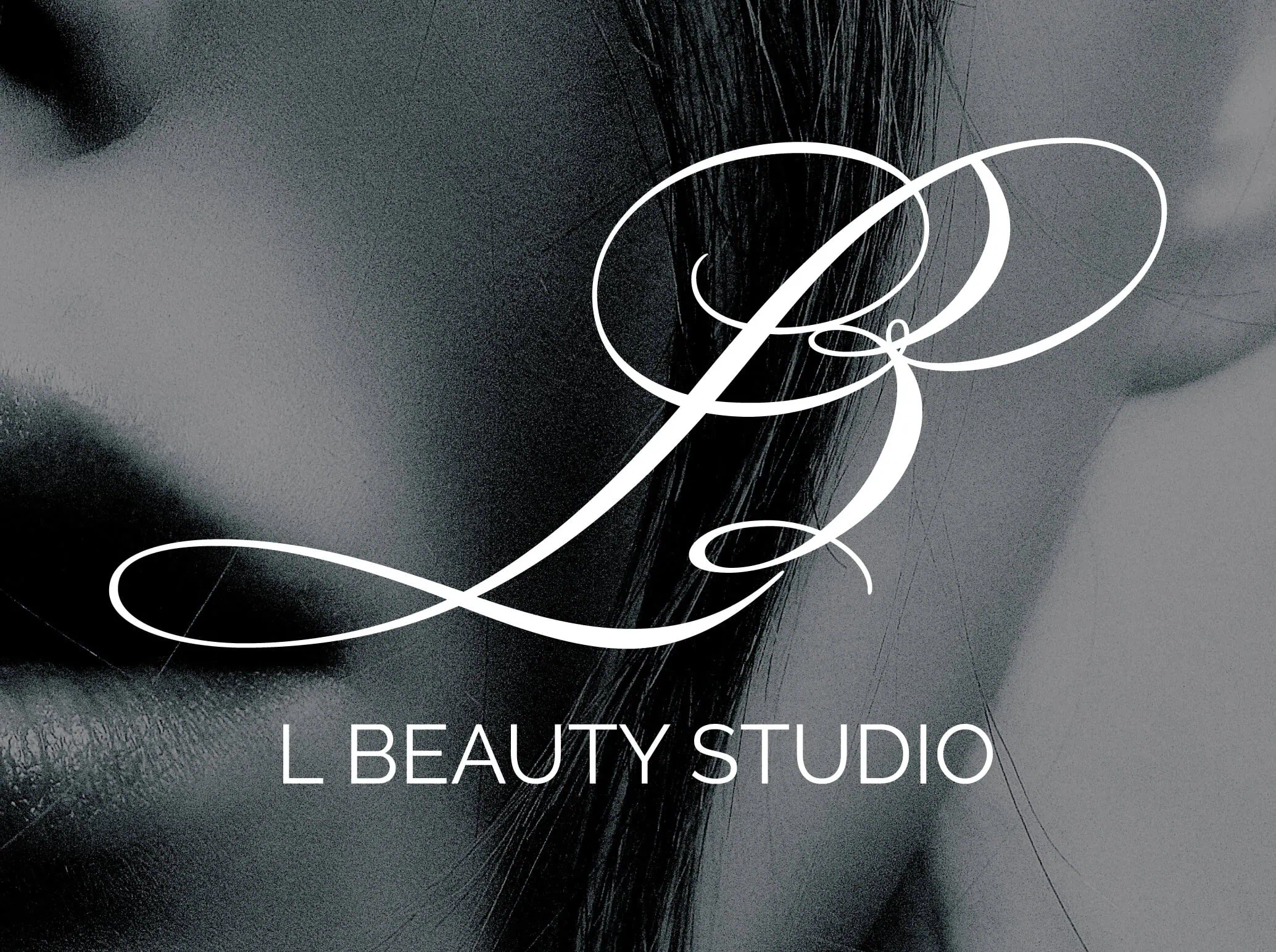 L Beauty Studio logo white out of a black and white close-up image of a beautiful face.