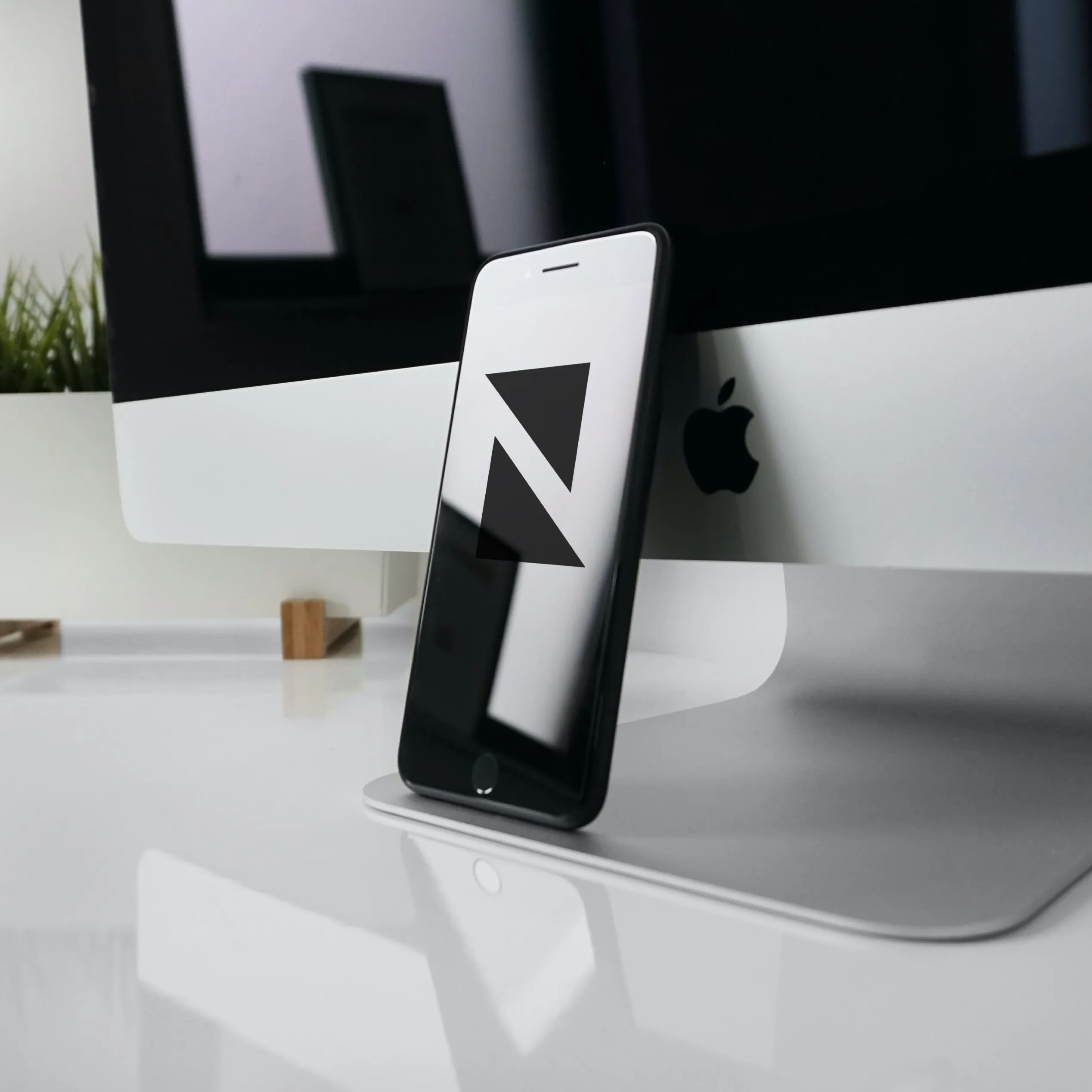 Newall Consulting logo shown on a mobile phone beside an iMac