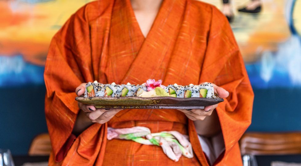 Woman in kimono holding a plate of sushi