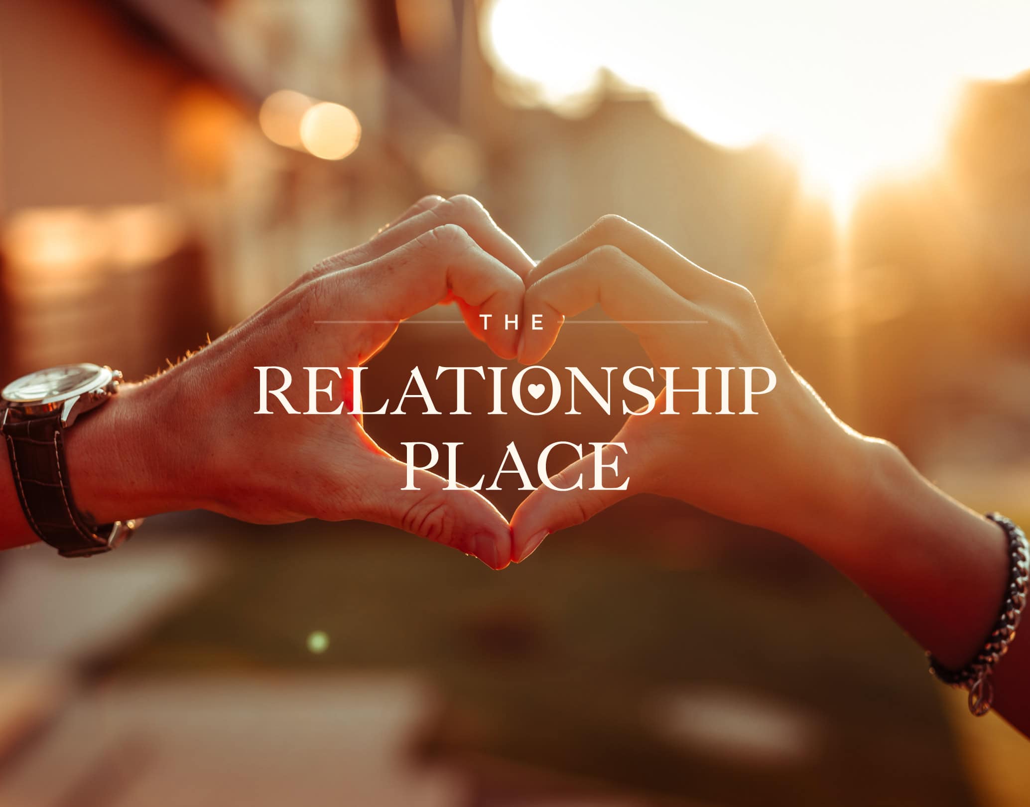 The Relationship logo overlaying an image of hands making a heart shape
