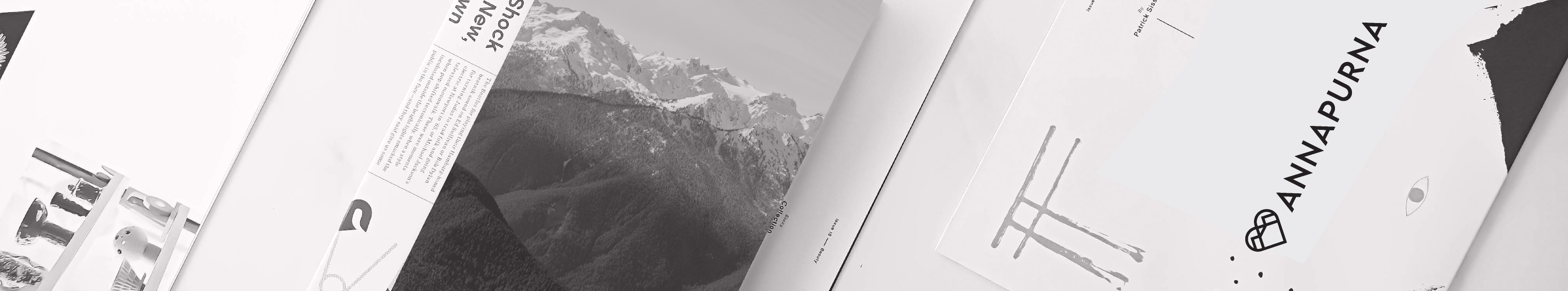 Flat lay of Annapurna branded print materials and magazine spreads featuring mountain imagery in monochrome.
