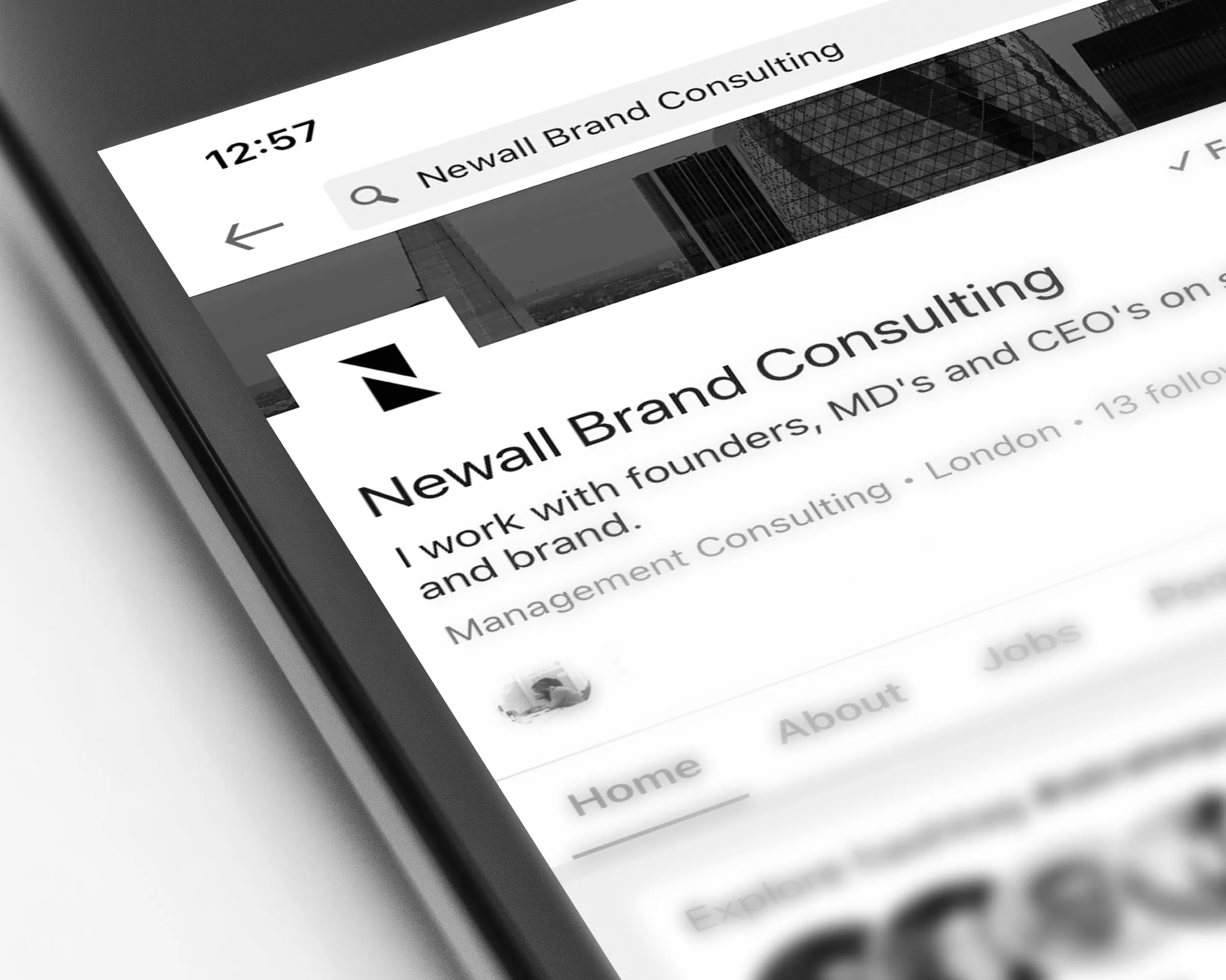 Angled close-up of a smartphone showing the LinkedIn profile page for Newall Brand Consulting with its logo and header image.